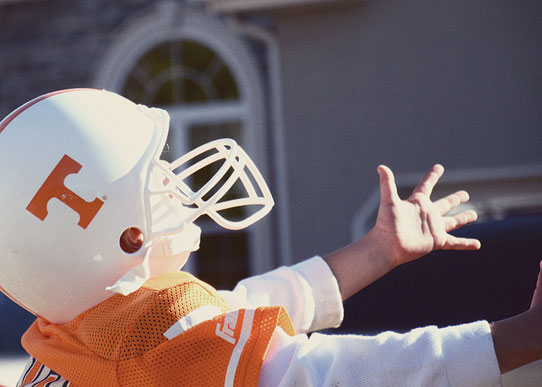 boy in Tennessee Vols uniform catching football