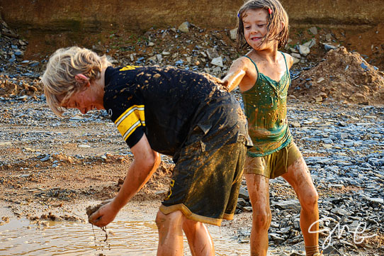 Girl slinging mud at her brother