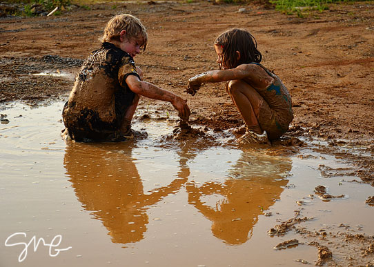 Brother and sister playing in mud